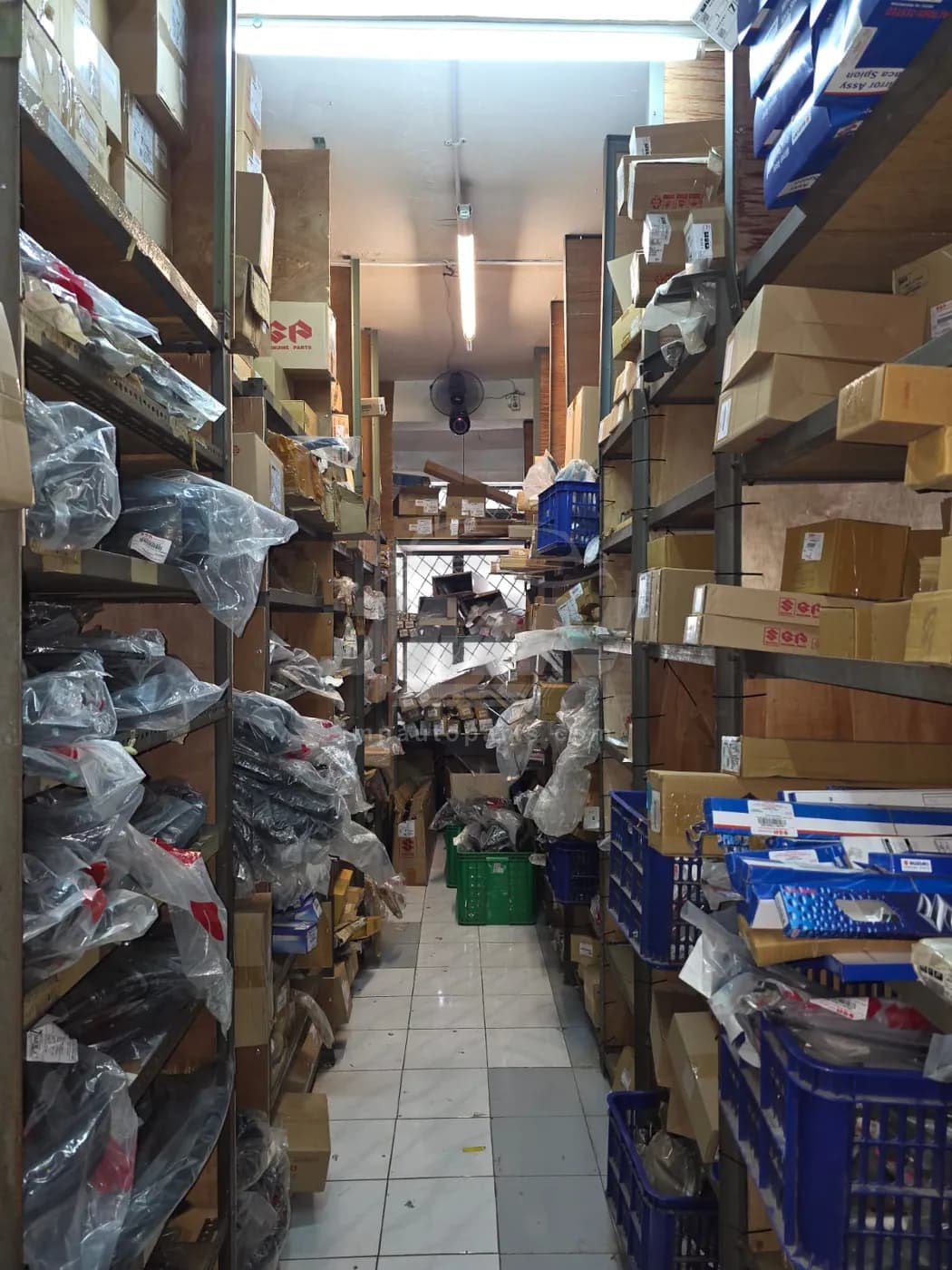 Second warehouse aisle with bagged and boxed OEM components sorted across wooden shelving